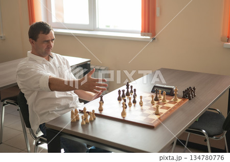 Middle aged Caucasian man playing chess.  134780776