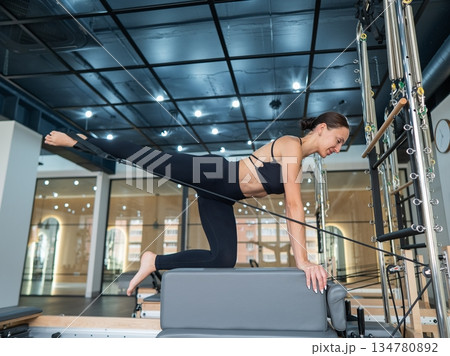 Caucasian woman doing leg exercise on reformer machine.  134780892