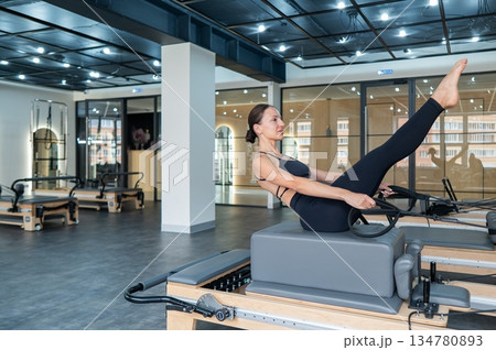 Caucasian woman doing exercises on reformer machine. Caucasian woman doing exercises on reformer machine. 134780893