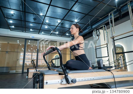 Caucasian woman doing exercises on reformer machine.  134780900