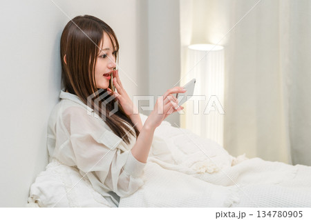 夜ベッドに入りスマホを見る若いアジア人女性 夜ベッドに入りスマホを見る若いアジア人女性 134780905