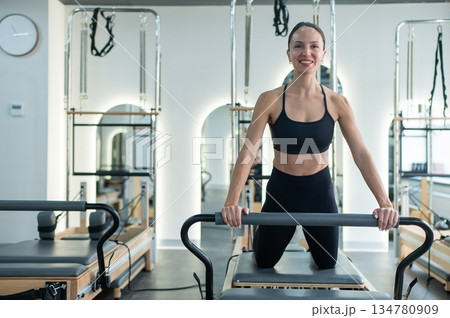 Caucasian woman doing exercises on reformer machine. Caucasian woman doing exercises on reformer machine. 134780909