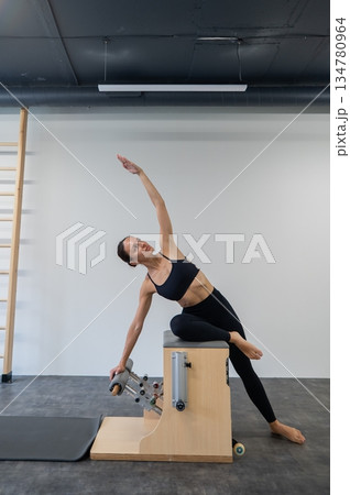 Caucasian woman doing Pilates on classic chair. Caucasian woman doing Pilates on classic chair. 134780964