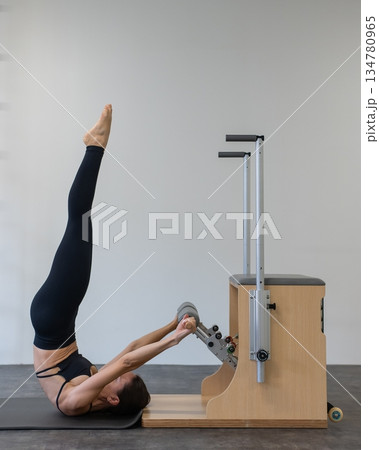 Caucasian woman doing Pilates on classic chair. Caucasian woman doing Pilates on classic chair. 134780965