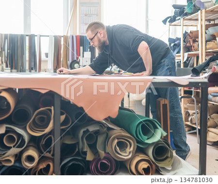 Caucasian bearded man working as a tanner in a workshop. Caucasian bearded man working as a tanner in a workshop. 134781030