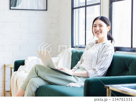 リビングでパソコンを使う若い女性 リビングでパソコンを使う若い女性 134781331
