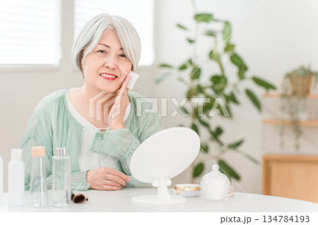 肌を保湿するためにスキンケアするグレイヘアーのシニア女性 肌を保湿するためにスキンケアするグレイヘアーのシニア女性 134784193