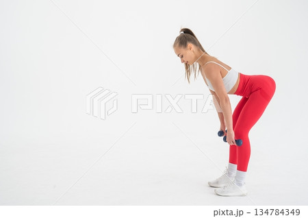 Young woman doing exercise with dumbbells on white background. 134784349