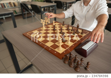 Close up of hands of middle aged caucasian man playing chess.  134784398