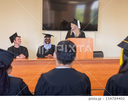 A young woman stands at the lectern and delivers a graduation speech to her classmates. A young woman stands at the lectern and delivers a graduation speech to her classmates. 134784402