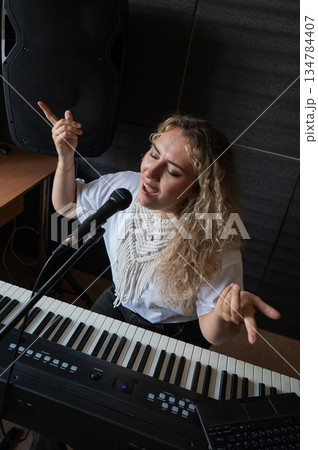 Caucasian woman singing into microphone and recording herself on laptop. Caucasian woman singing into microphone and recording herself on laptop. 134784407