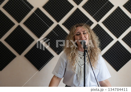 Caucasian woman singing into microphone in music studio.  134784411