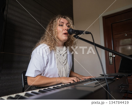 Caucasian woman singing into microphone and playing synthesizer. Caucasian woman singing into microphone and playing synthesizer. 134784419