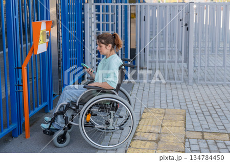 A woman in a wheelchair uses a call button for people with disabilities. A woman in a wheelchair uses a call button for people with disabilities. 134784450