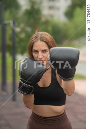 A Caucasian woman practices boxing outdoors. A Caucasian woman practices boxing outdoors. 134784489