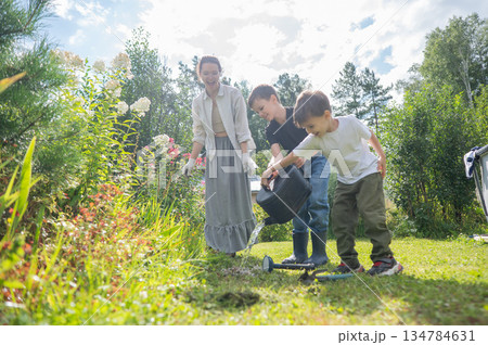 Caucasian woman tending her garden with her sons. Caucasian woman tending her garden with her sons. 134784631