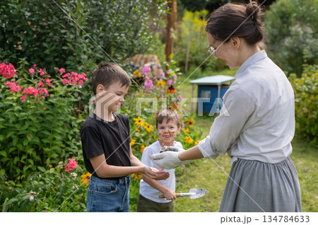 Caucasian woman tending her garden with her sons.  134784633