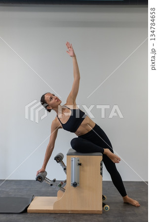 Caucasian woman doing Pilates on classic chair. Caucasian woman doing Pilates on classic chair. 134784658