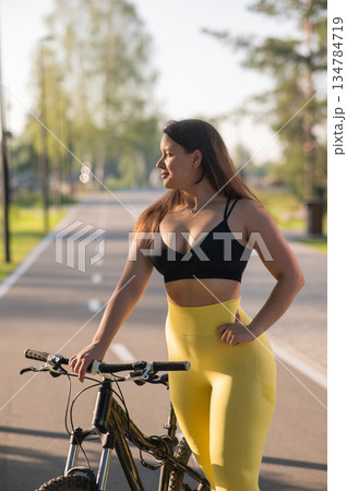 Curvy Caucasian Woman Riding Bicycle in Park.  134784719