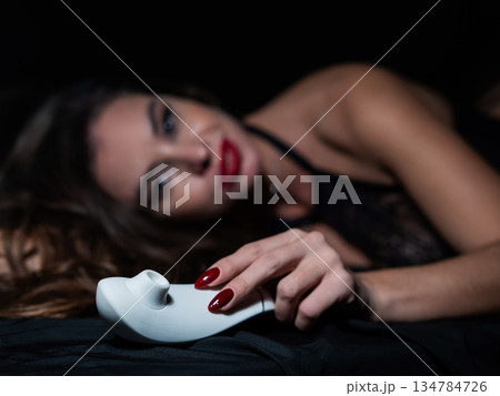 Woman in lace lingerie holding white clitoral vacuum stimulator. Woman in lace lingerie holding white clitoral vacuum stimulator. 134784726
