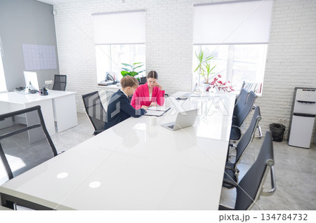 Man and woman talking while sitting at desk in office. Man and woman talking while sitting at desk in office. 134784732