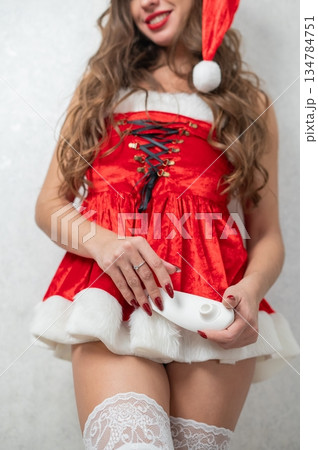 Caucasian woman dressed as Santa Claus holding white vacuum stimulator. Caucasian woman dressed as Santa Claus holding white vacuum stimulator. 134784751