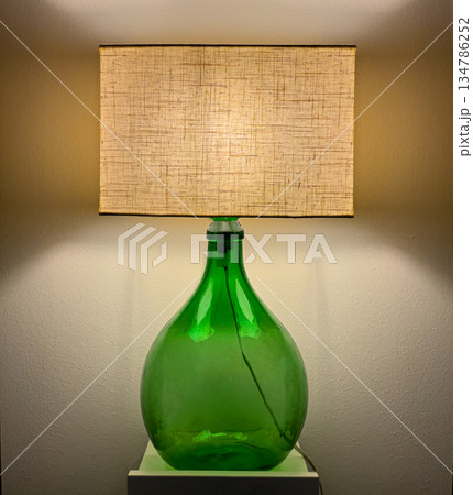 Upcycled green glass bottle lamp illuminating wall Upcycled green glass bottle lamp illuminating wall 134786252