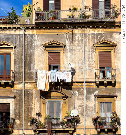 Weathered apartment building facade with laundry drying on balcony in italy Weathered apartment building facade with laundry drying on balcony in italy 134786254