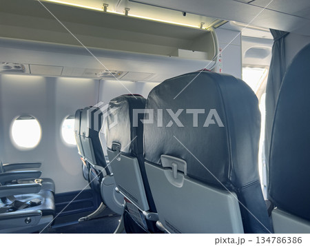 Empty airplane cabin interior showing passenger seats and windows 134786386
