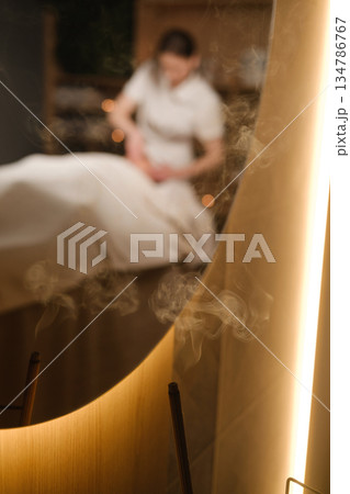 Relaxing massage in a quiet spa with soft lighting and soothing atmosphere and incense Relaxing massage in a quiet spa with soft lighting and soothing atmosphere and incense 134786767