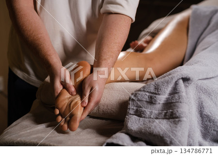 The master massages the feet of the foot. The expert foot massage technique, performed in a calm spa environment, is aimed at relaxing and relieving stress for the client. The master massages the feet of the foot. The expert foot massage technique, performed in a calm spa environment, is aimed at relaxing and relieving stress for the client. 134786771