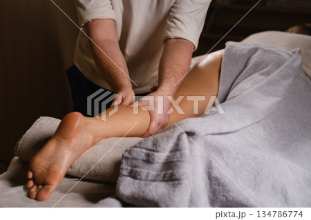 Massage therapist provides a relaxing leg massage in a serene spa environment during a wellness session Massage therapist provides a relaxing leg massage in a serene spa environment during a wellness session 134786774