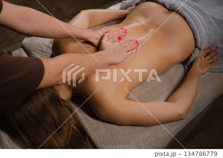 A massage therapist provides a relaxing back massage in a soothing spa setting. 134786779