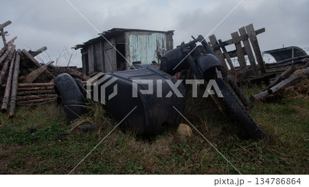 abandoned farm machinery and tanks near shed, rusted tires and toppled barrels, collapsed wooden fence abandoned farm machinery and tanks near shed, rusted tires and toppled barrels, collapsed wooden fence 134786864