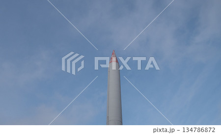 tall rocket monument pointing into sky, red-tipped nose and smooth steel casing, frontal vertical perspective 134786872