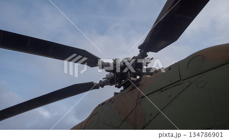 close-up helicopter rotor hub and blades showing mechanical linkages, chipped paint, weathered camouflage close-up helicopter rotor hub and blades showing mechanical linkages, chipped paint, weathered camouflage 134786901