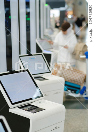 Travelers use self-service kiosks at the airport for check-in while waiting for their flights on a busy weekday afternoon 134786920
