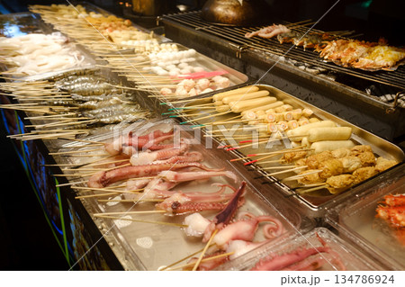 Grilled octopus skewers displayed at a lively night market in an Asian city during a bustling evening street food event 134786924