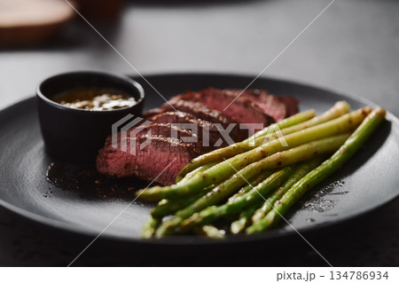 New york steak with asparagus on black plate with pesto sauce New york steak with asparagus on black plate with pesto sauce 134786934