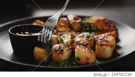eat roasted scallops with baked potatoes on black plate eat roasted scallops with baked potatoes on black plate 134787116