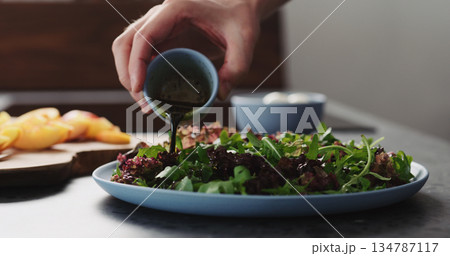 man making salad with nectarines and mozzarella on a blue plate on concrete countertop on kitchen, add dressing man making salad with nectarines and mozzarella on a blue plate on concrete countertop on kitchen, add dressing 134787117