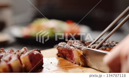 man slicing new york steak on olive wood board man slicing new york steak on olive wood board 134787118