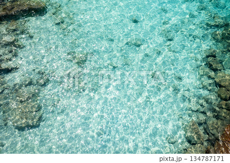 The clear turquoise water reflecting sunlight on a serene beach on a sunny day encourages relaxation and enjoyment of the beauty of nature 134787171