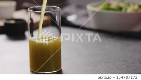pour apple celery juice in glass on concrete countertop with copy space 134787172