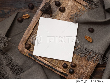 Square card on wooden tray near brown decor and grey linen cloth top view, boho mockup 134787765