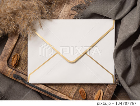 Envelope on wooden tray near brown decor and grey linen cloth top view, boho mockup 134787767