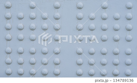 塗装された鉄板に並ぶリベットとボルトの頭、橋梁の重厚なテクスチャ背景 134789136