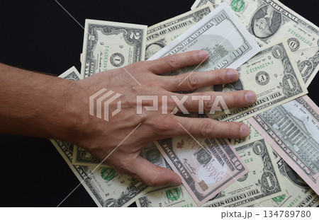 Paper US dollar bills covered by a man's hand Paper US dollar bills covered by a man's hand 134789780