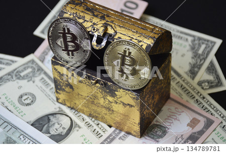 bitcoin coin and a chest next to a pack of dollars on a black background 134789781
