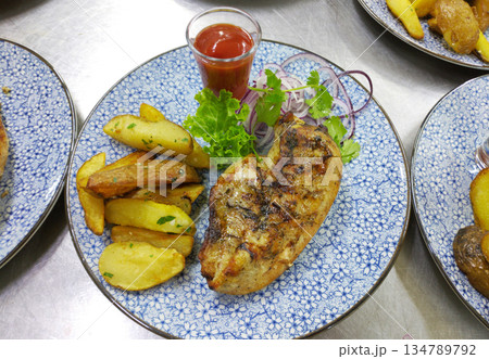 Grilled chicken breast and potato wedges with lettuce and sauce Grilled chicken breast and potato wedges with lettuce and sauce 134789792